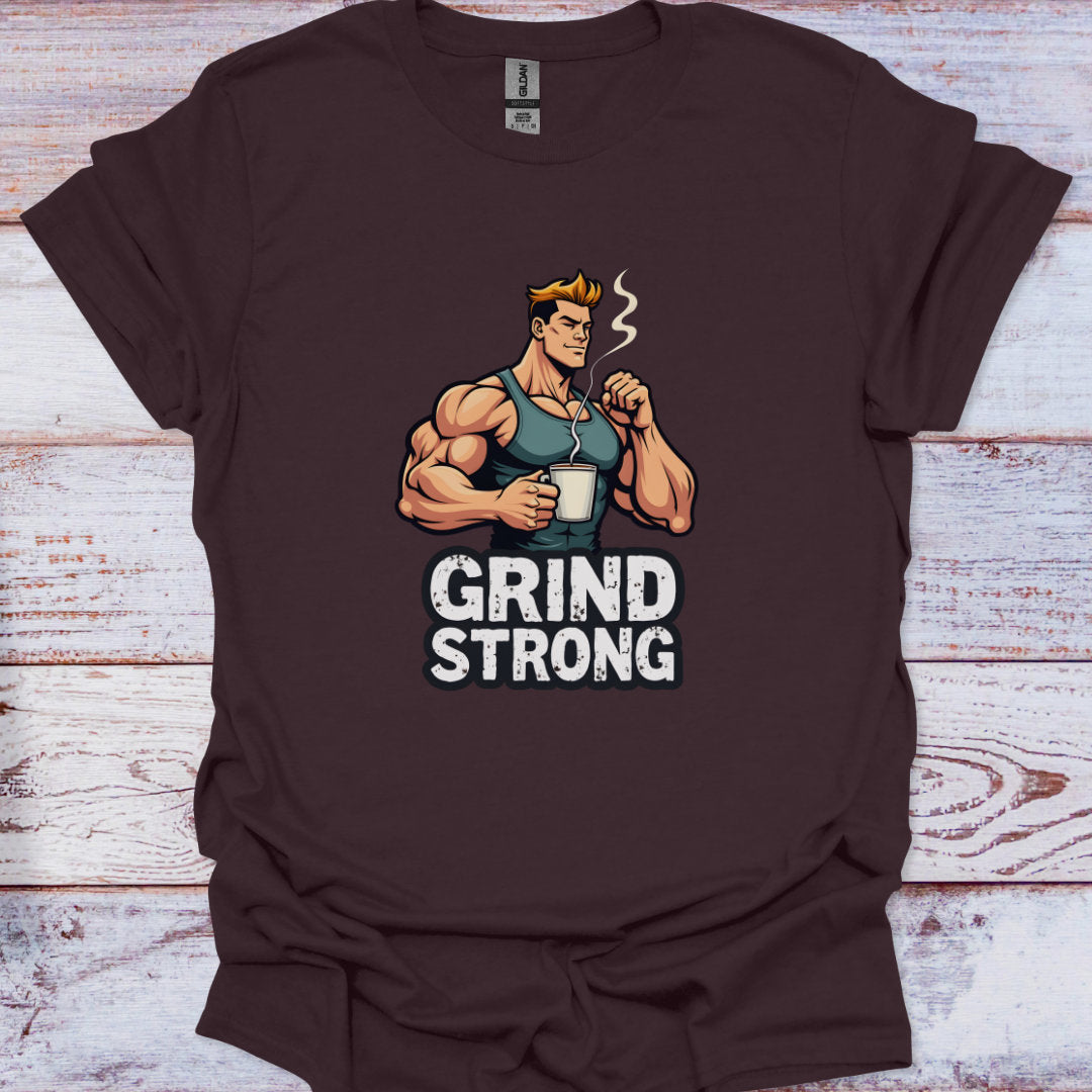 Brown t-shirt with a graphic of a muscular man holding a coffee cup and 'Grind Strong' text on a wooden surface.
