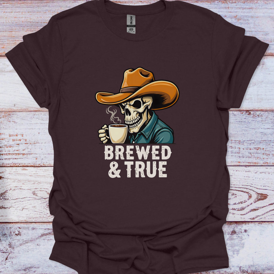 Brown t-shirt with a skeleton wearing a cowboy hat and holding a coffee cup, text 'BREWED & TRUE' on a wooden surface.
