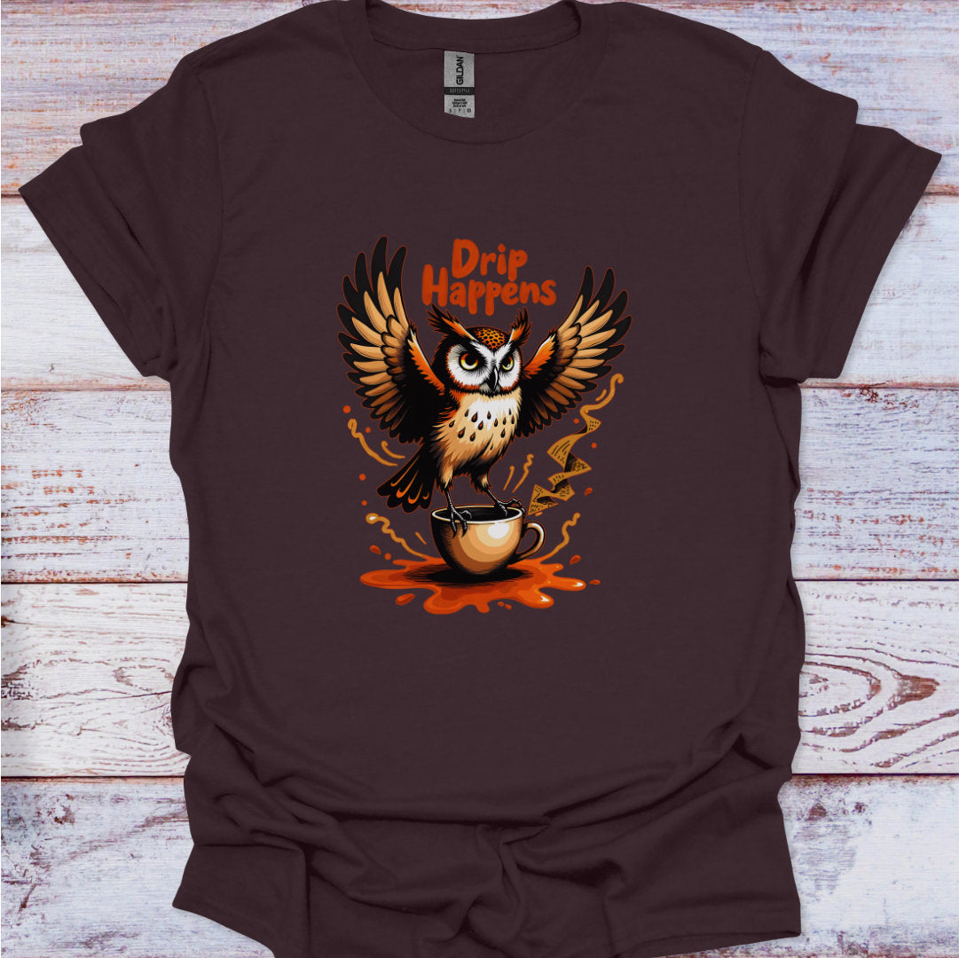 Brown t-shirt with an owl graphic and 'Drip Happens' text on a wooden surface