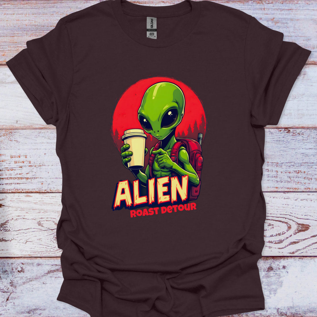 Brown t-shirt with an alien graphic holding a coffee cup on a wooden surface