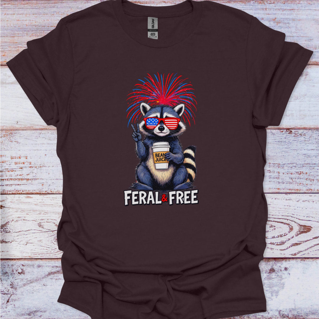 Brown t-shirt with a raccoon graphic wearing sunglasses and a red, white, and blue headband on a wooden surface.