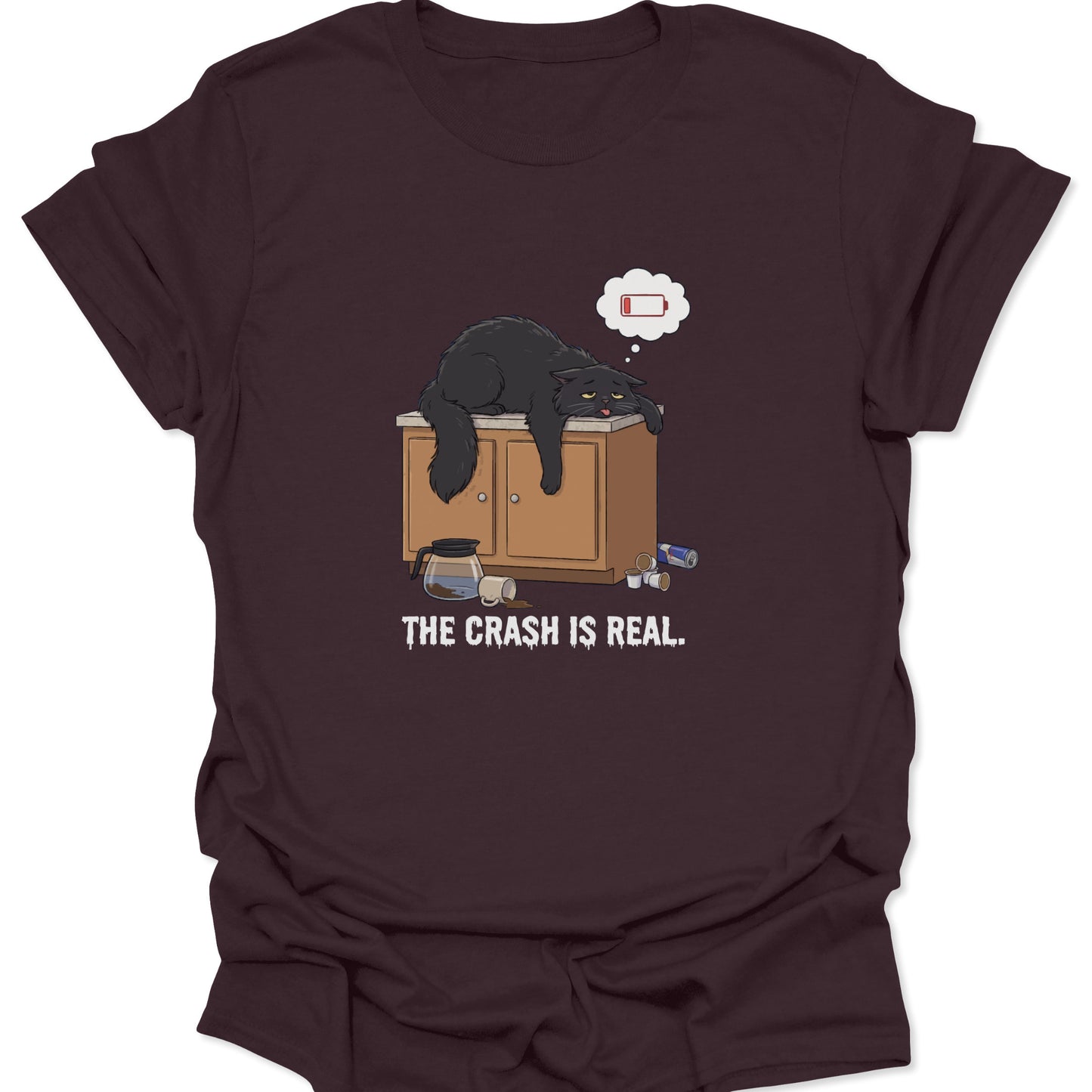 Graphic tee on dark chocolate brown fabric showing a tired black cat slumped over a counter with a low battery thought bubble.