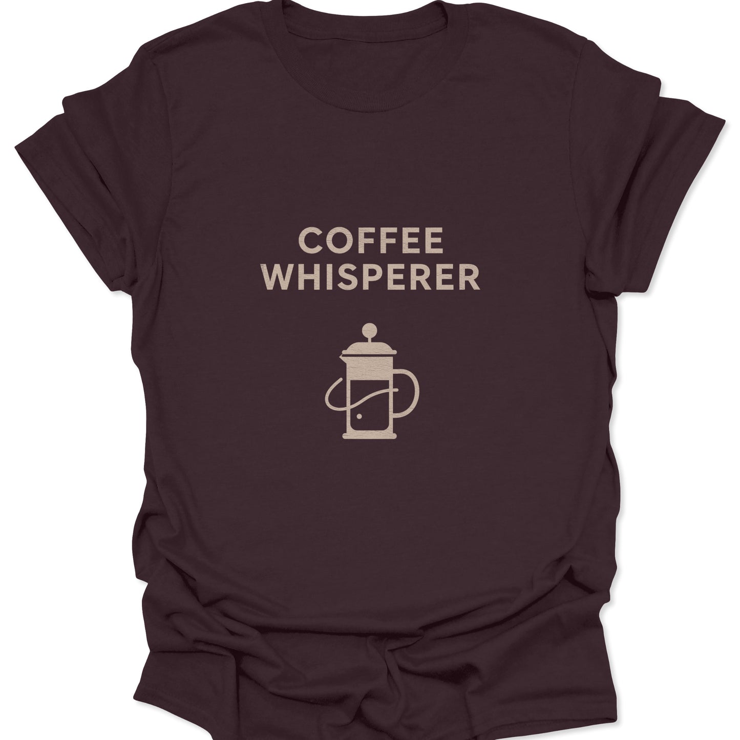 Graphic tee in dark chocolate brown featuring a tan minimalist French Press illustration and "Coffee Whisperer" typography.