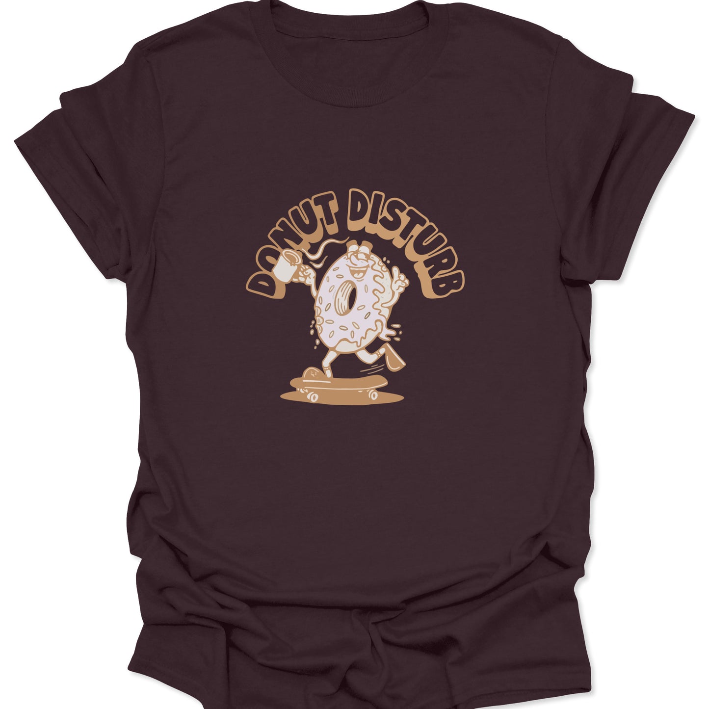 Graphic tee on dark brown fabric featuring a cartoon donut character skateboarding with a coffee mug and "Donut Disturb" text in tan.