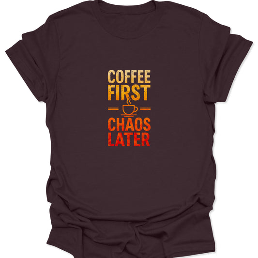 Distressed text graphic tee with a yellow-orange to red gradient reading 'COFFEE FIRST CHAOS LATER' split by a steaming cup icon, against a rich dark chocolate brown background.