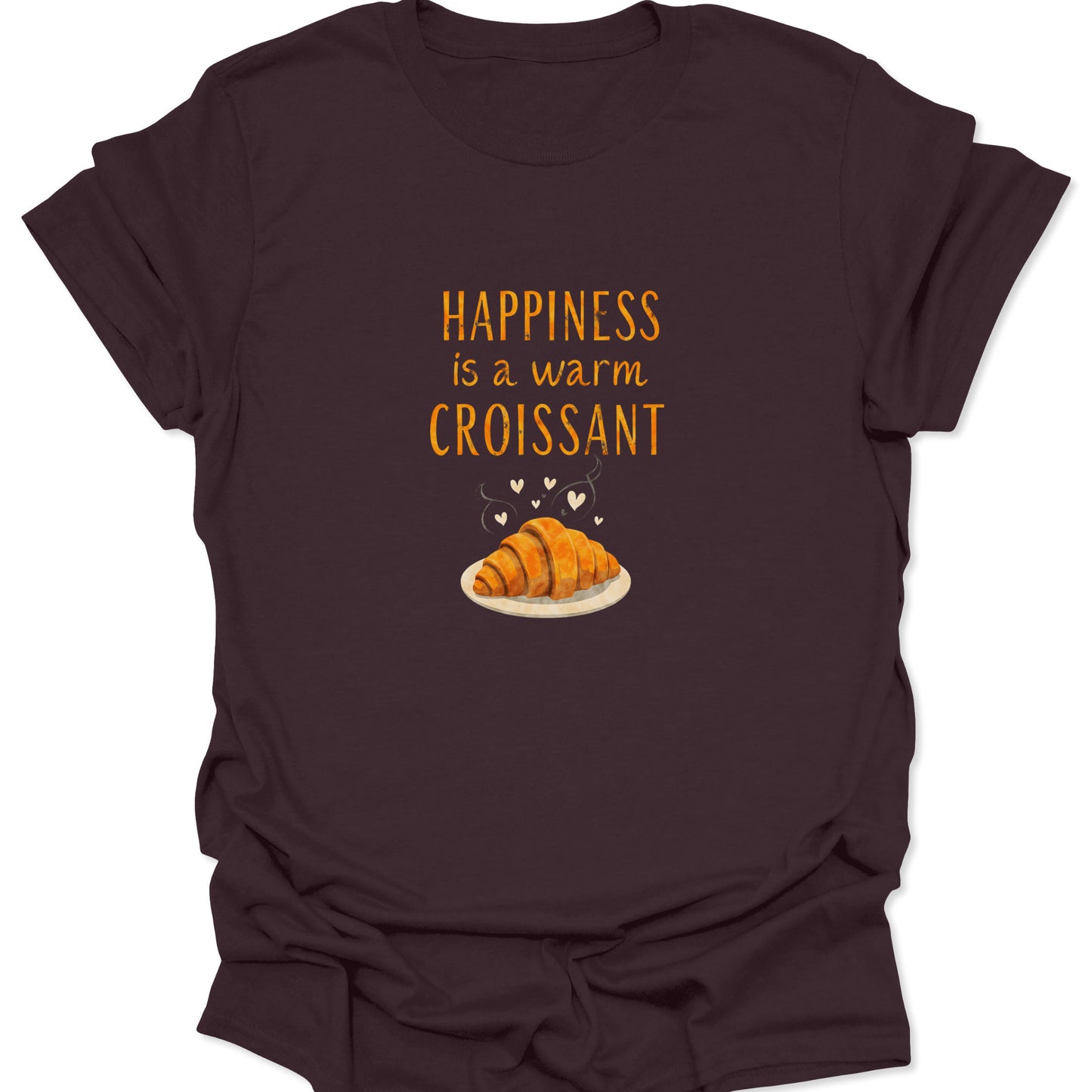 Dark brown graphic tee featuring a prominent golden croissant illustration and the bold, warm orange phrase "Happiness is a warm Croissant."