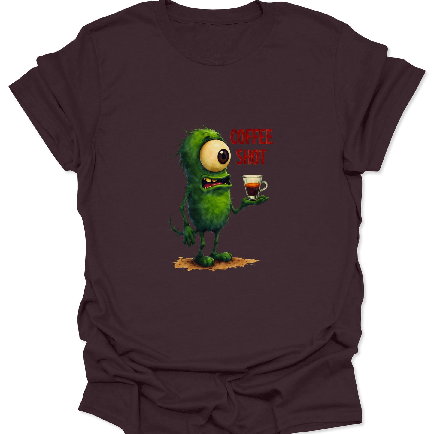 Graphic t-shirt featuring a hyper-green, one-eyed alien creature needing coffee, printed on a dark chocolate brown fabric.