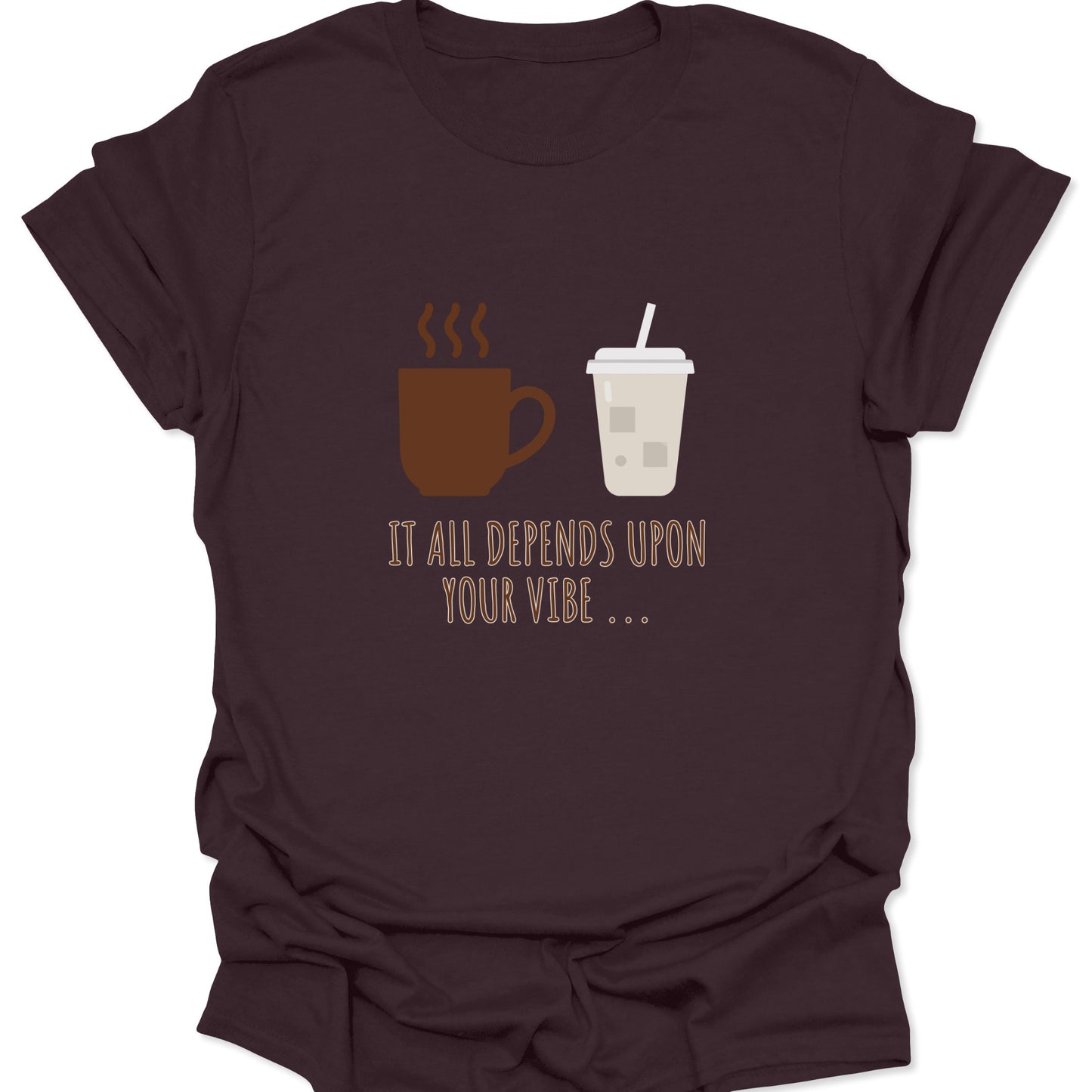 Graphic tee on dark chocolate brown fabric featuring a brown steaming coffee mug and a light beige iced coffee cup with the text "IT ALL DEPENDS UPON YOUR VIBE..." in thin brown lettering.