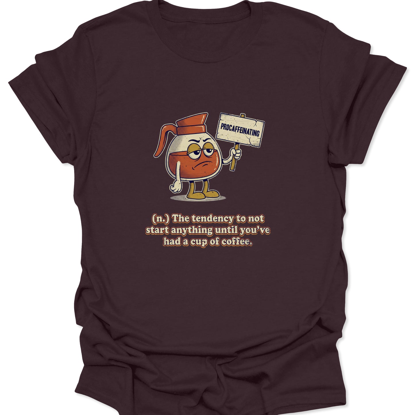 A dark chocolate brown graphic t-shirt featuring a cartoon coffee carafe with a grumpy face holding a "PROCAFFEINATING" sign above a dictionary-style definition.