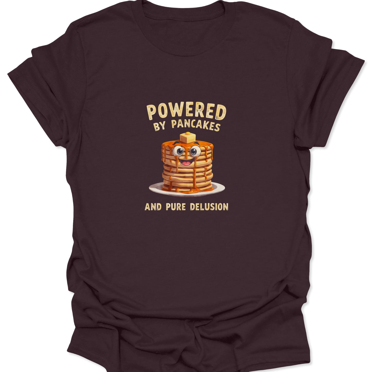 Funny graphic tee on Dark Chocolate Brown fabric showing a cartoon pancake stack with googly eyes and text Powered By Pancakes And Pure Delusion.