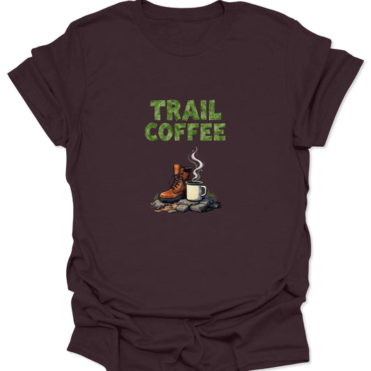 Deep brown shirt featuring the green TRAIL COFFEE text and a realistic illustration of a hiking boot and hot coffee cup on a rocky, moss-covered ground.