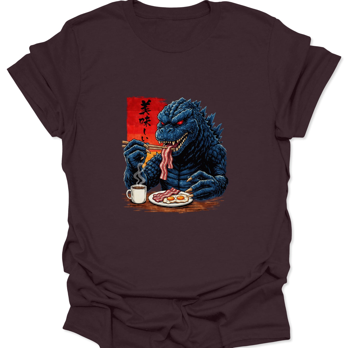 Graphic tee on a chocolate brown fabric featuring a blue scaly monster eating breakfast with chopsticks and a mug of coffee.