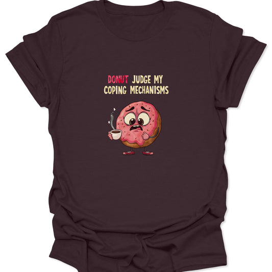 Graphic t-shirt on a dark chocolate brown background featuring a nervous pink-frosted donut holding a steaming coffee cup with the text "Donut Judge My Coping Mechanisms."