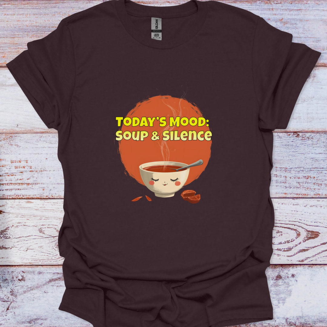 Brown t-shirt with a graphic of a bowl of soup and text 'TODAY'S MOOD: SOUP & SILENCE' on a wooden surface.