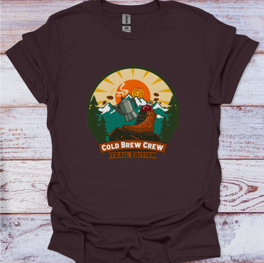 Brown t-shirt with 'Cold Brew Crew Trail Edition' graphic on a wooden surface
