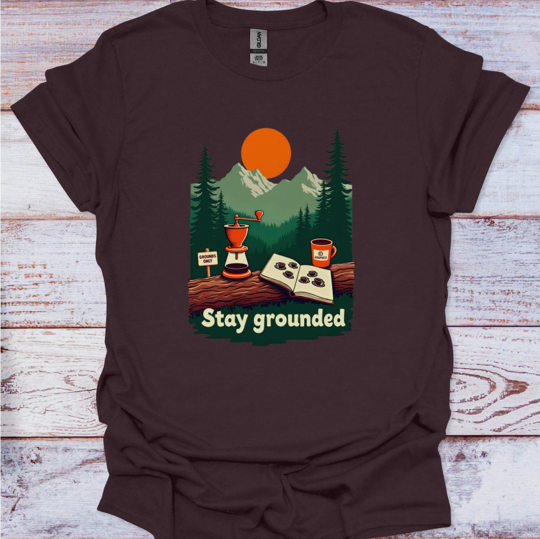 Brown t-shirt with nature-themed graphic and 'Stay grounded' text on a wooden surface