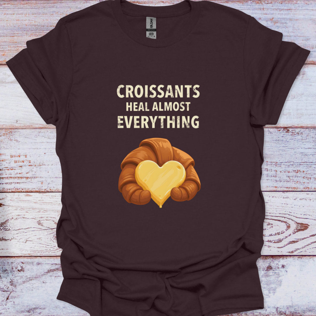 Brown t-shirt with a croissant graphic and text on a wooden surface