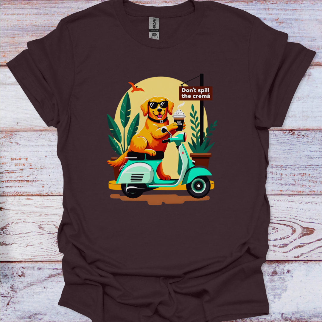 Brown t-shirt with a graphic of a dog on a scooter and penguin, with text 'Don't spill the crema', on a wooden surface.