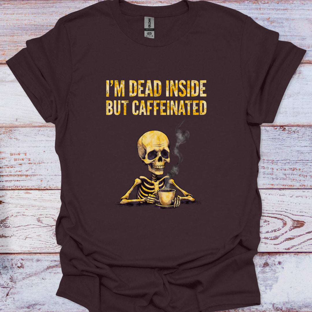 Brown t-shirt with a skeleton holding a coffee cup and text 'I'm dead inside but caffeinated' on a wooden surface.