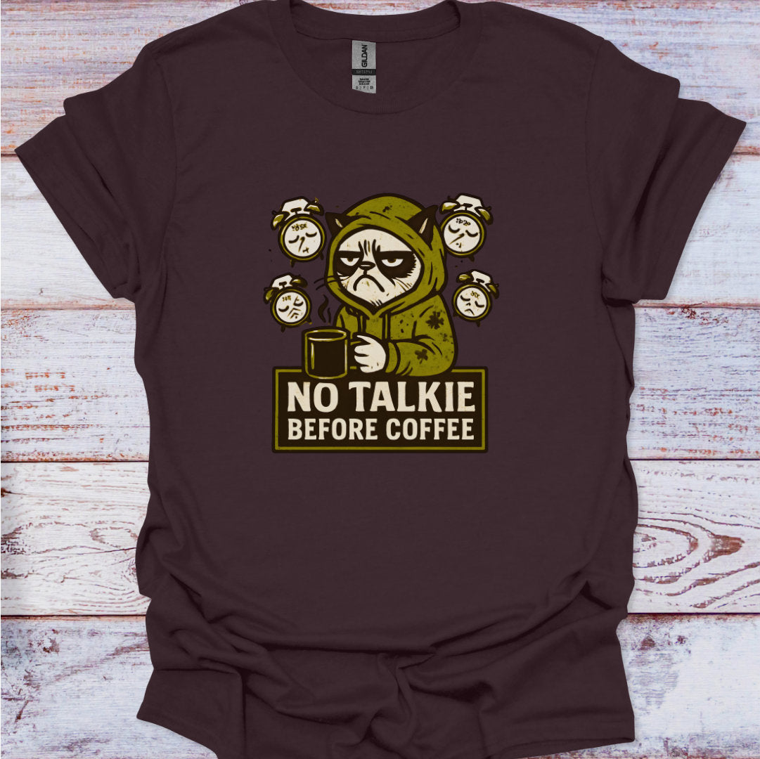 Brown t-shirt with a graphic of a character holding a coffee cup and text 'No Talkie Before Coffee' on a wooden surface.