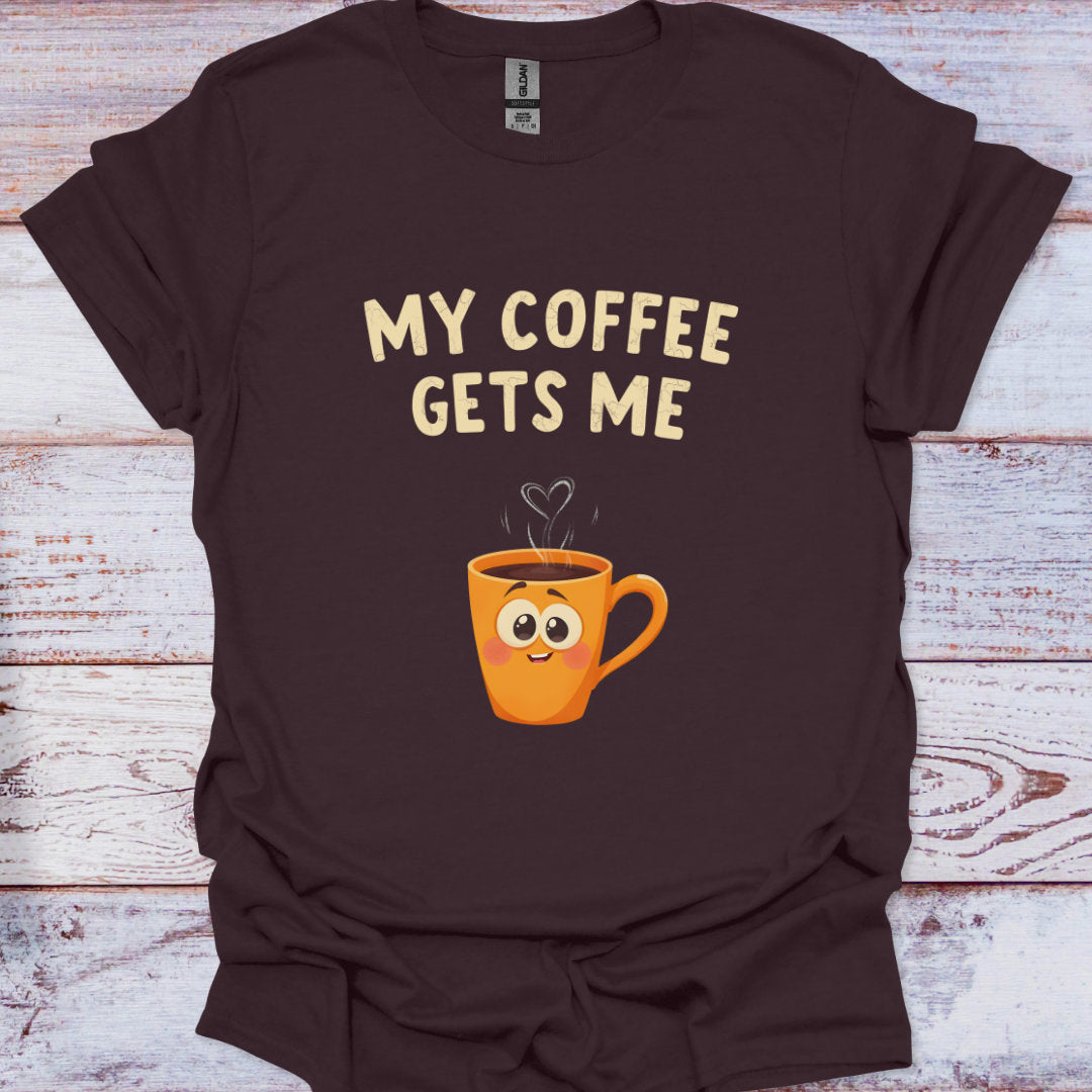 Brown t-shirt with a cartoon coffee mug and 'My Coffee Gets Me' text on a wooden surface