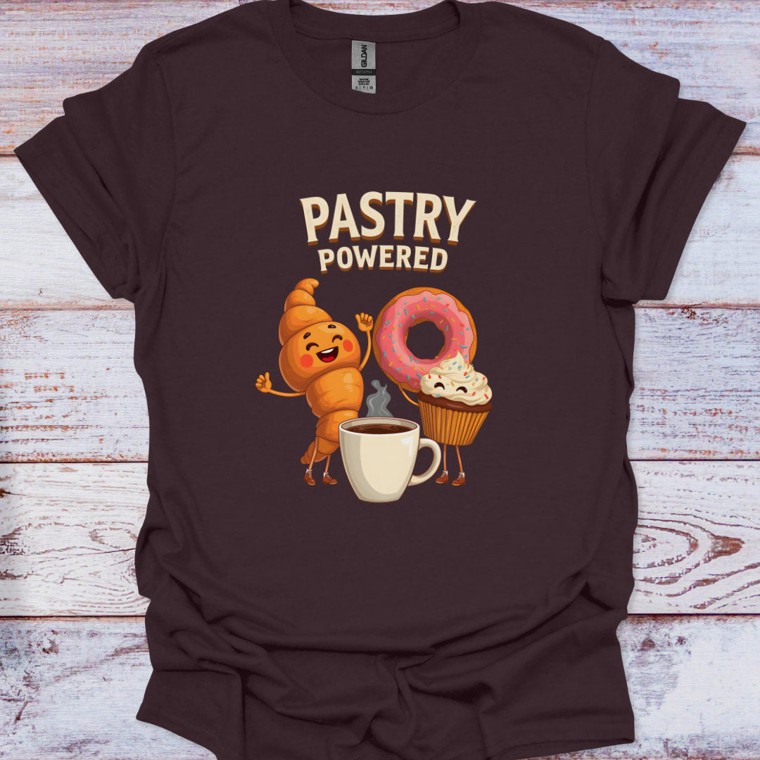 Brown t-shirt with 'Pastry Powered' graphic design featuring a cookie, donut, and cupcake on a wooden background.