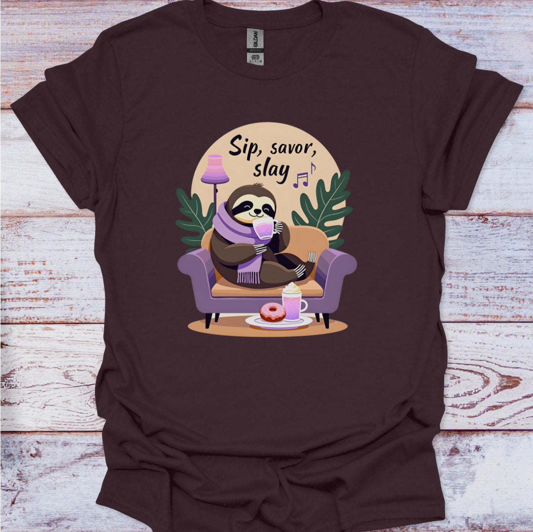 Brown t-shirt with a sloth graphic and text 'Sip, savor, slay' on a wooden surface