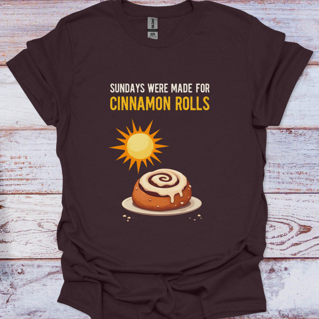 Brown t-shirt with cinnamon roll graphic and text on a wooden surface