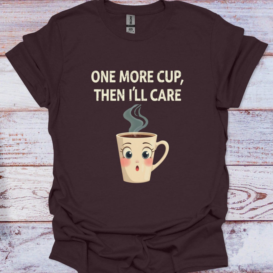 Brown t-shirt with a cartoon coffee cup and text 'One more cup, then I'll care' on a wooden surface.