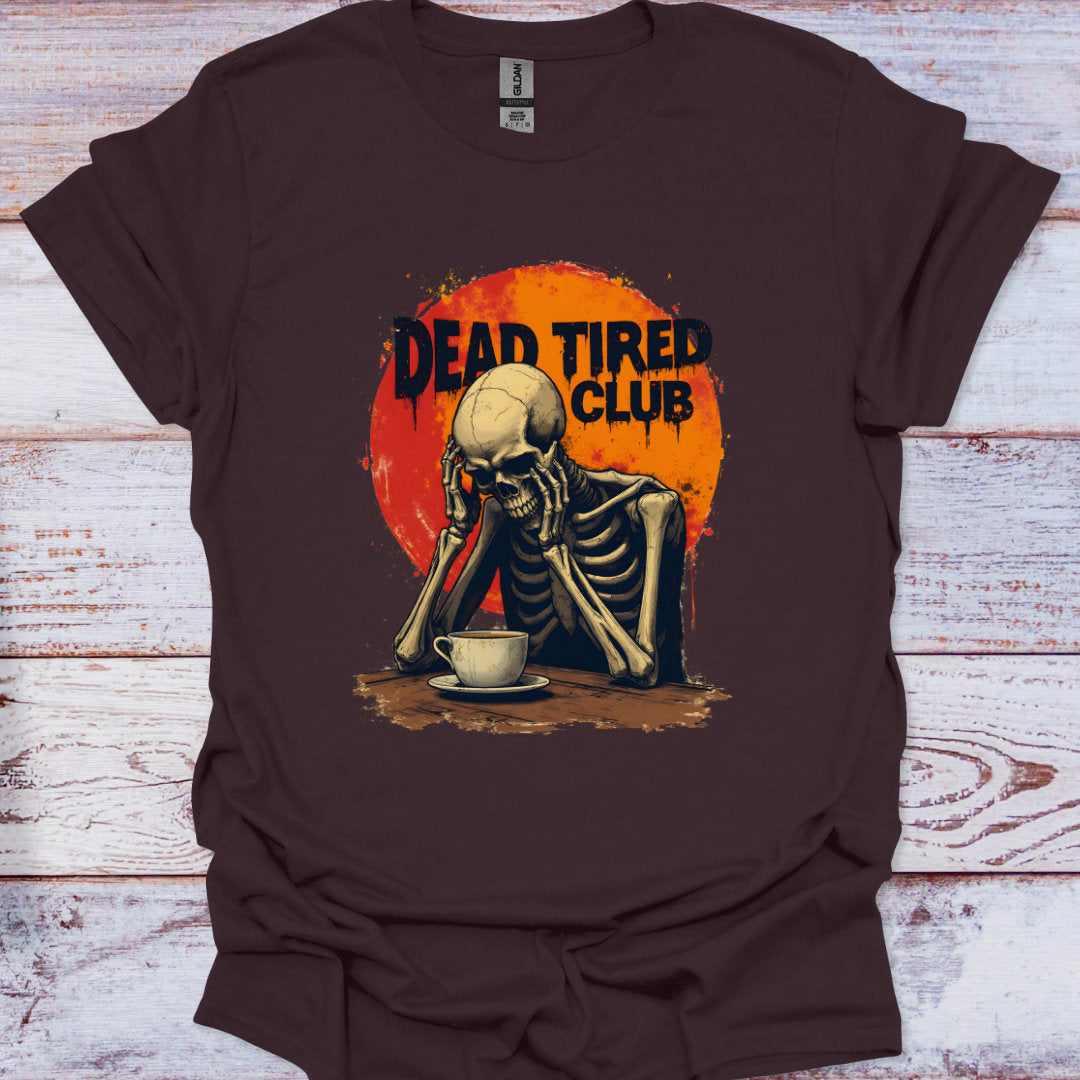 Brown t-shirt with a skeleton and 'Dead Tired Club' graphic on a wooden surface