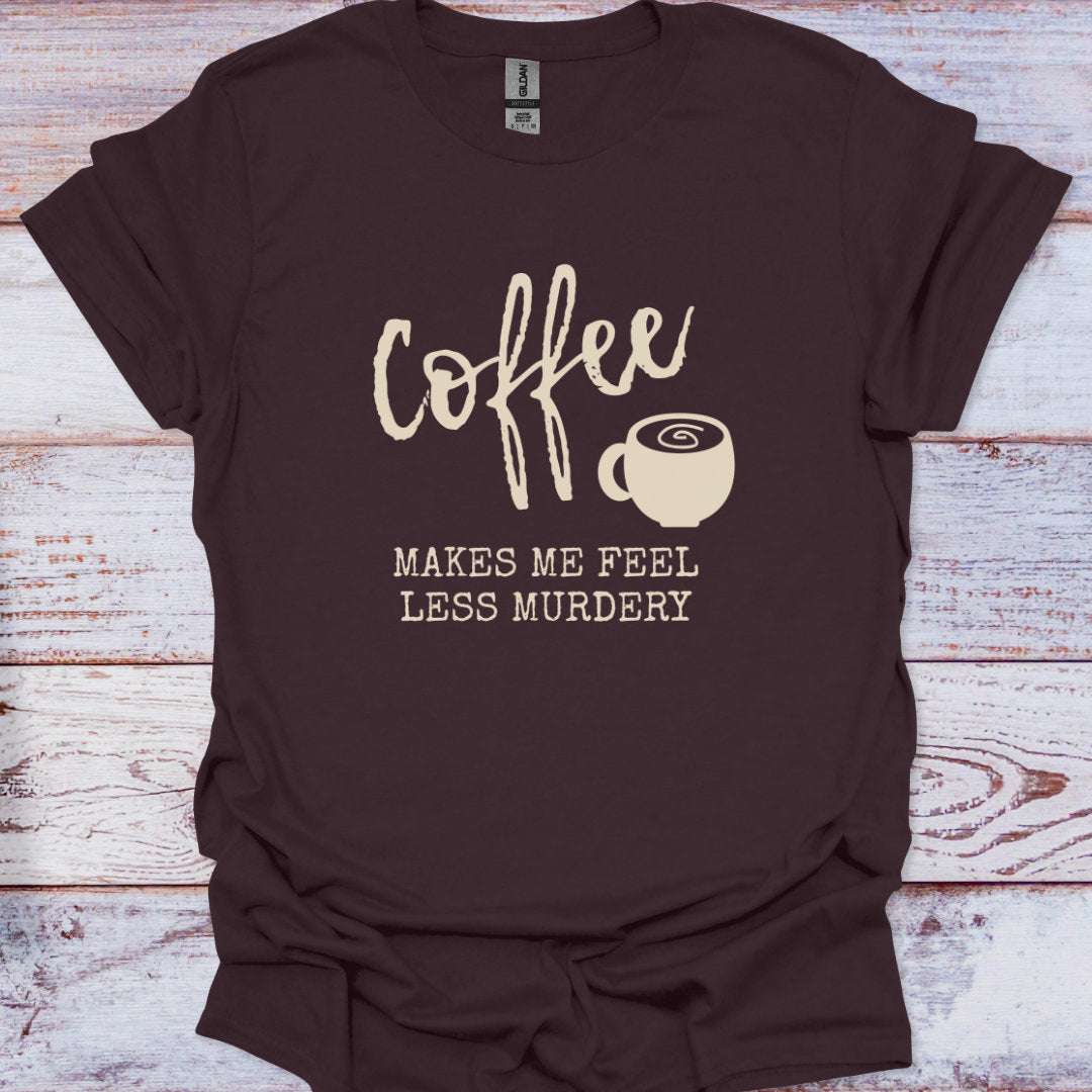 Brown t-shirt with 'Coffee makes me feel less murdery' text and coffee cup graphic on a wooden surface