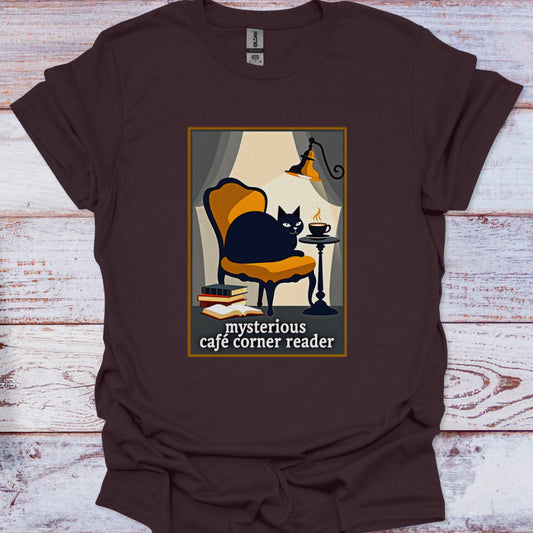Brown t-shirt with a graphic of a cat in a cafe and text 'mysterious cafe corner reader' on a wooden surface.