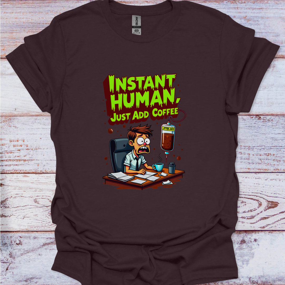 Brown t-shirt with a cartoon character and text 'Instant Human, Just Add Coffee' on a wooden surface.
