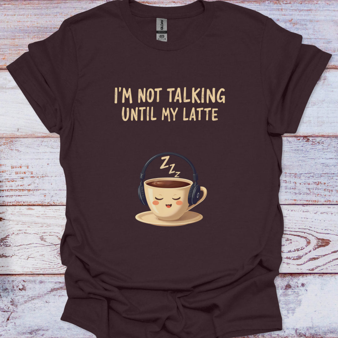 Brown t-shirt with a coffee cup graphic and text 'I'm not talking until my latte' on a wooden surface.