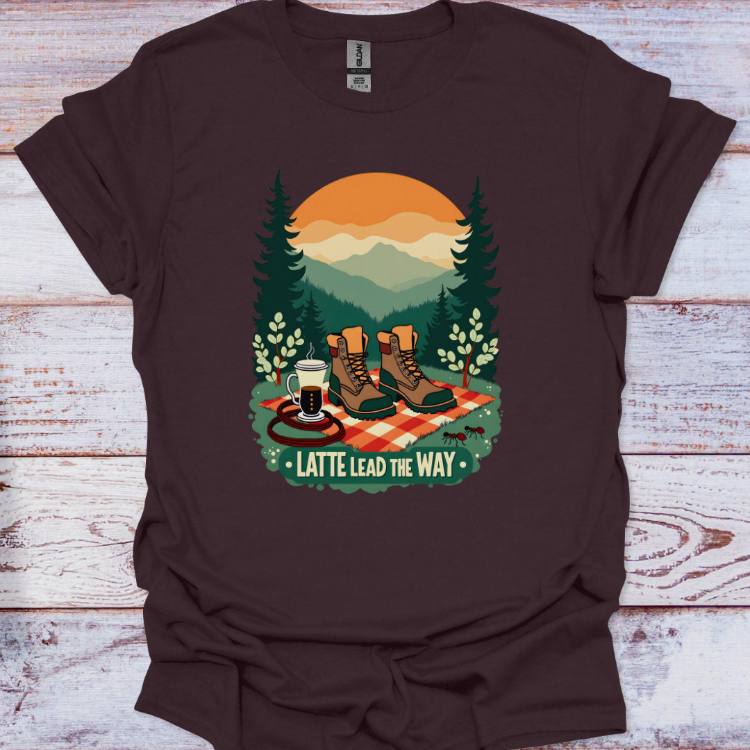 Brown t-shirt with a graphic of hiking boots, coffee, and trees on a wooden surface