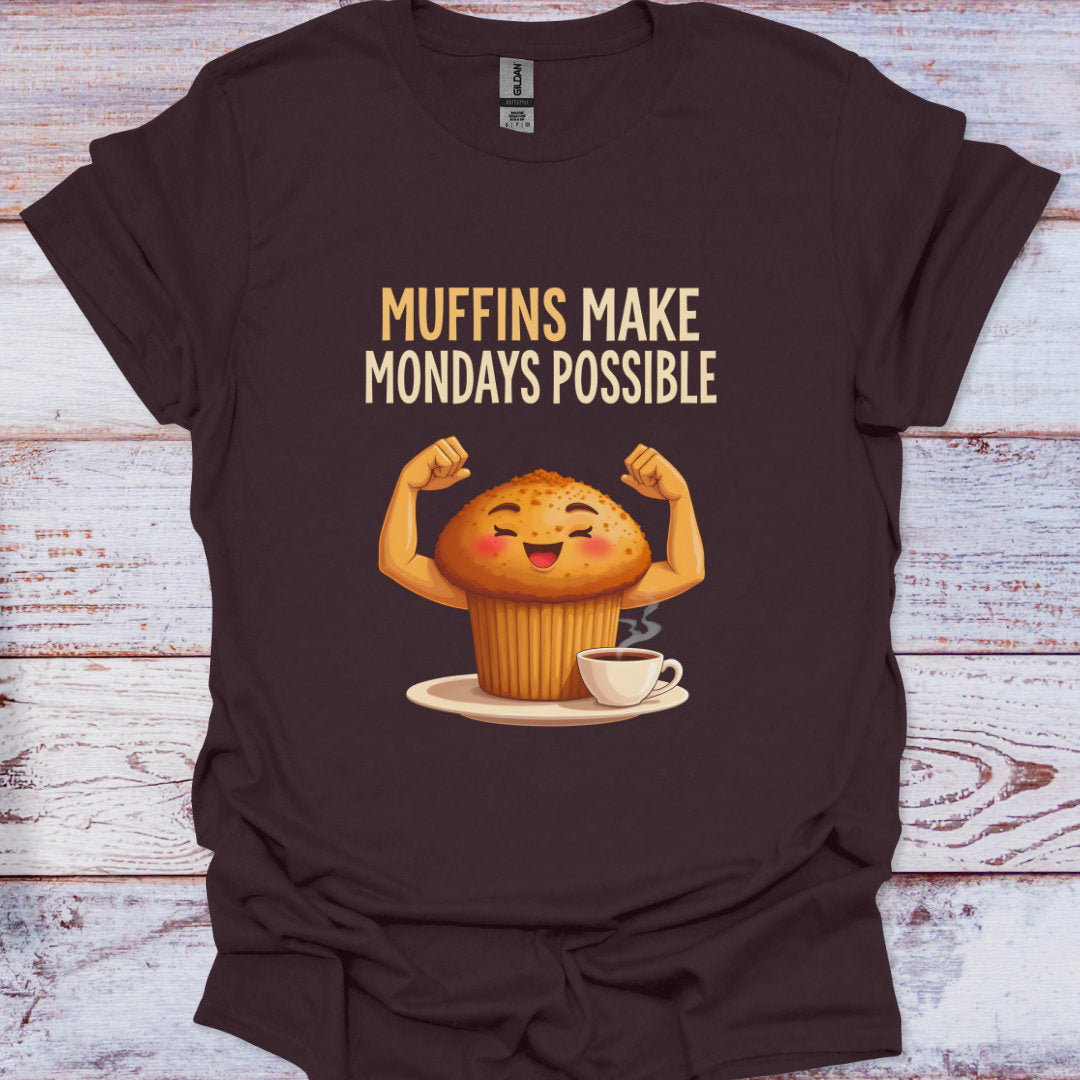 Brown t-shirt with a cartoon muffin flexing muscles and text 'Muffins Make Mondays Possible' on a wooden surface.