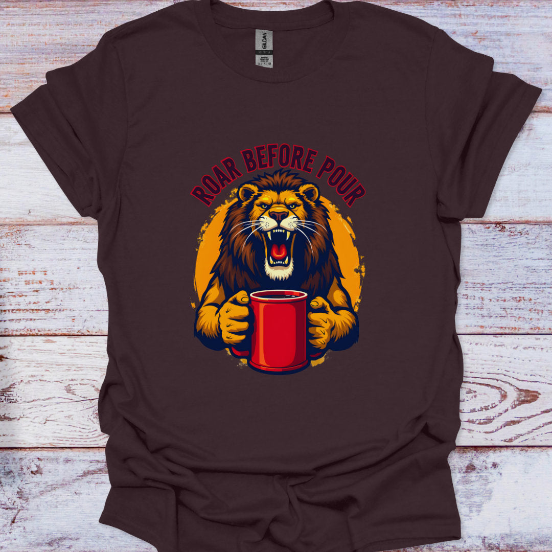 Brown t-shirt with a graphic of a lion holding a red cup and 'Roar Before Pour' text on a wooden surface.