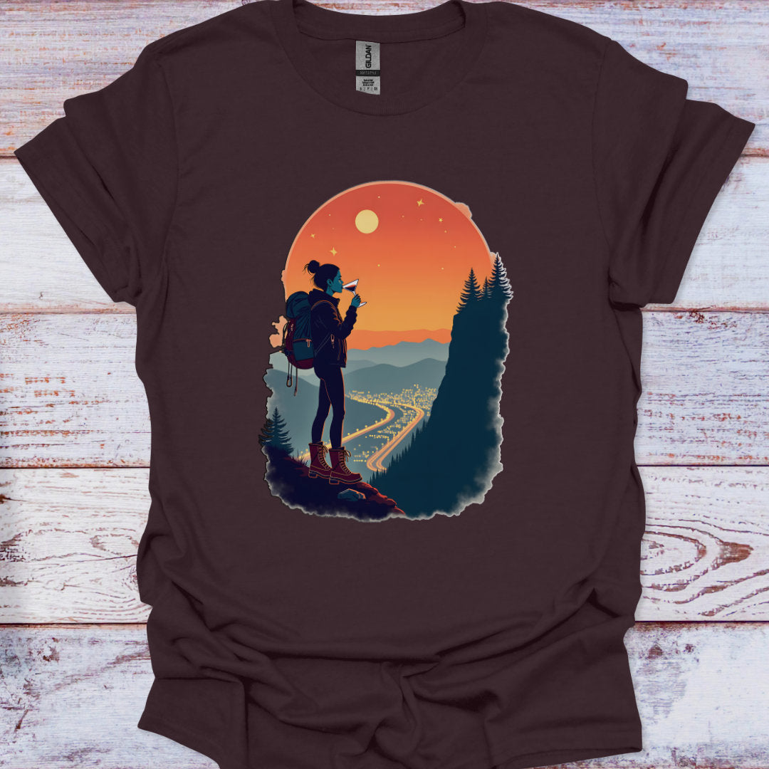Brown t-shirt with a graphic of a person with a backpack and a scenic landscape on a wooden surface.