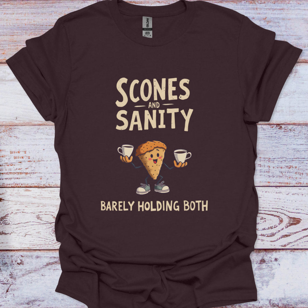 Brown t-shirt with 'Scones and Sanity Barely Holding Both' graphic on a wooden surface