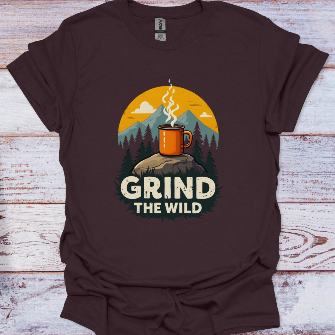 Brown t-shirt with a graphic of a mug on a rock with trees and mountains, and the text 'Grind the Wild' on a wooden surface.