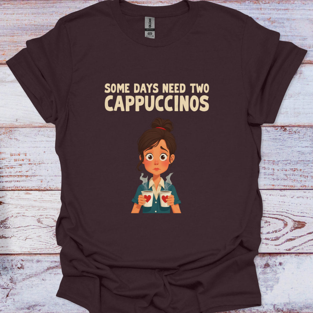 Brown t-shirt with cartoon character and text 'Some days need two Cappuccinos' on a wooden surface