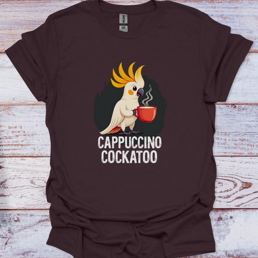 Brown t-shirt with a cockatoo holding a cup of coffee and 'Cappuccino Cockatoo' text on a wooden surface.