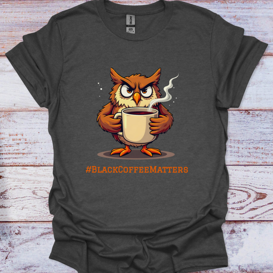 Gray t-shirt with an owl holding a coffee cup and '#BLACKCOFFEEMATTERS' text on a wooden surface.