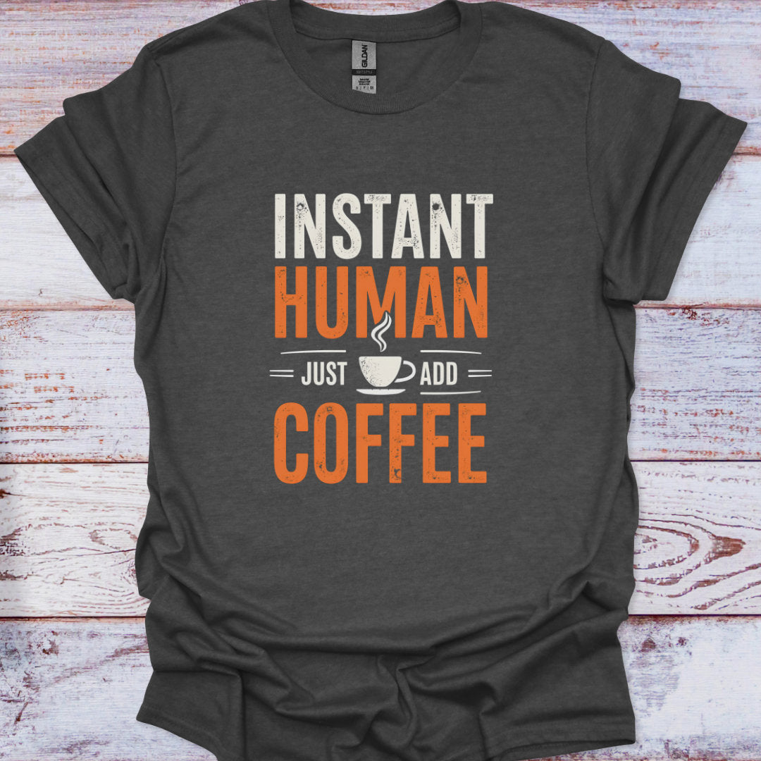 Dark gray t-shirt with 'Instant Human, Just Add Coffee' text on a wooden surface