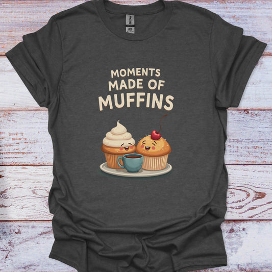 Dark gray t-shirt with cartoon muffins and 'Moments Made of Muffins' text on a wooden surface