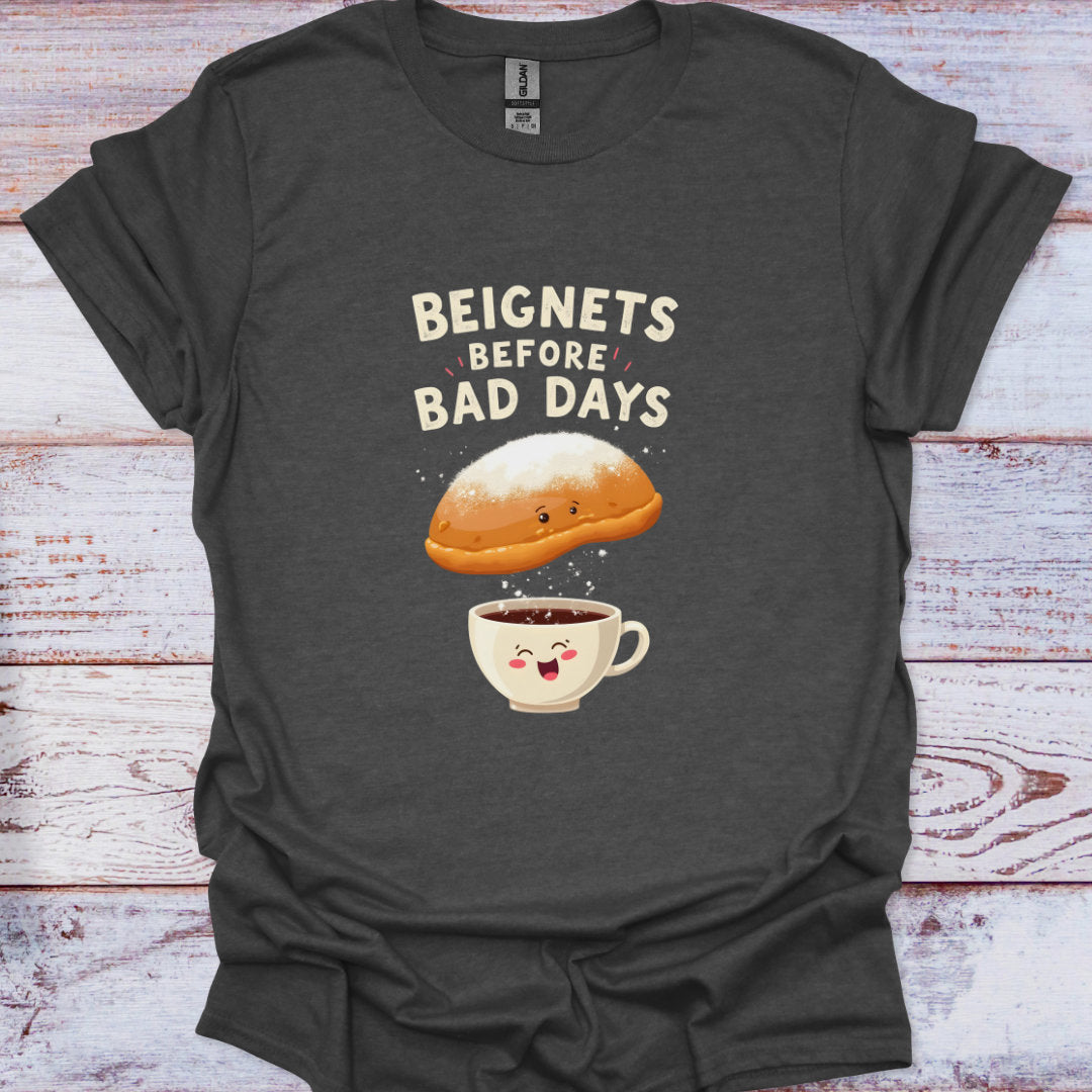 Dark gray t-shirt with a graphic of a beignet and coffee cup and text 'Beignets Before Bad Days' on a wooden surface.