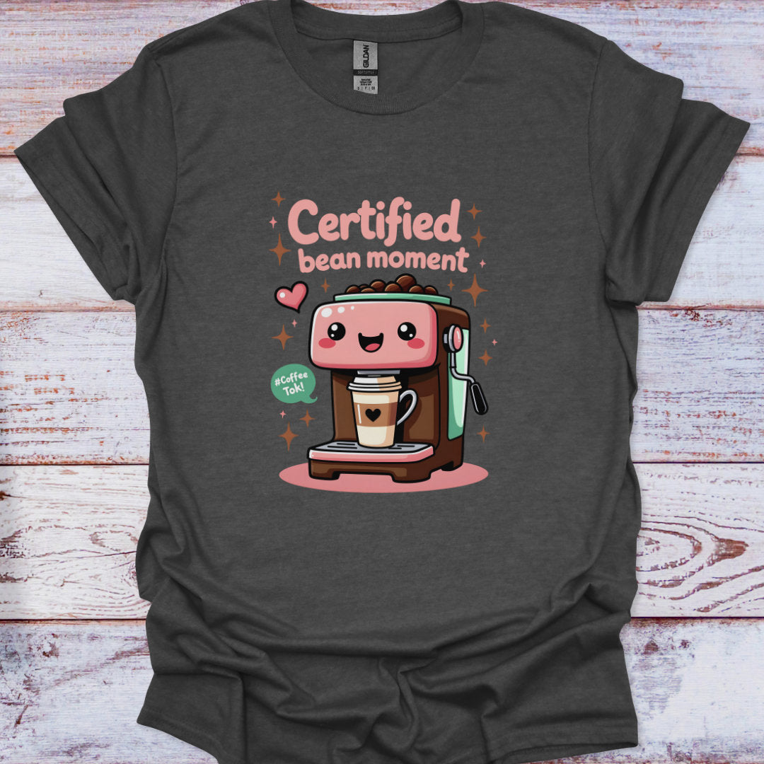 Dark gray t-shirt with a cartoon coffee machine and 'Certified bean moment' text on a wooden surface.