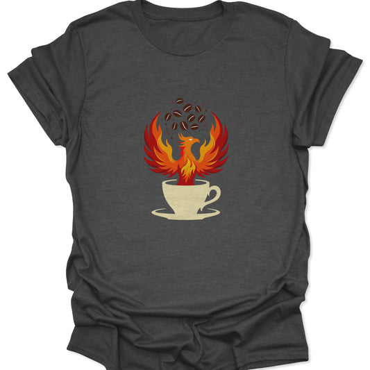 Graphic tee on a dark heather gray fabric background featuring a vibrant red and orange phoenix rising from a cream-colored coffee cup with dark coffee beans floating above.
