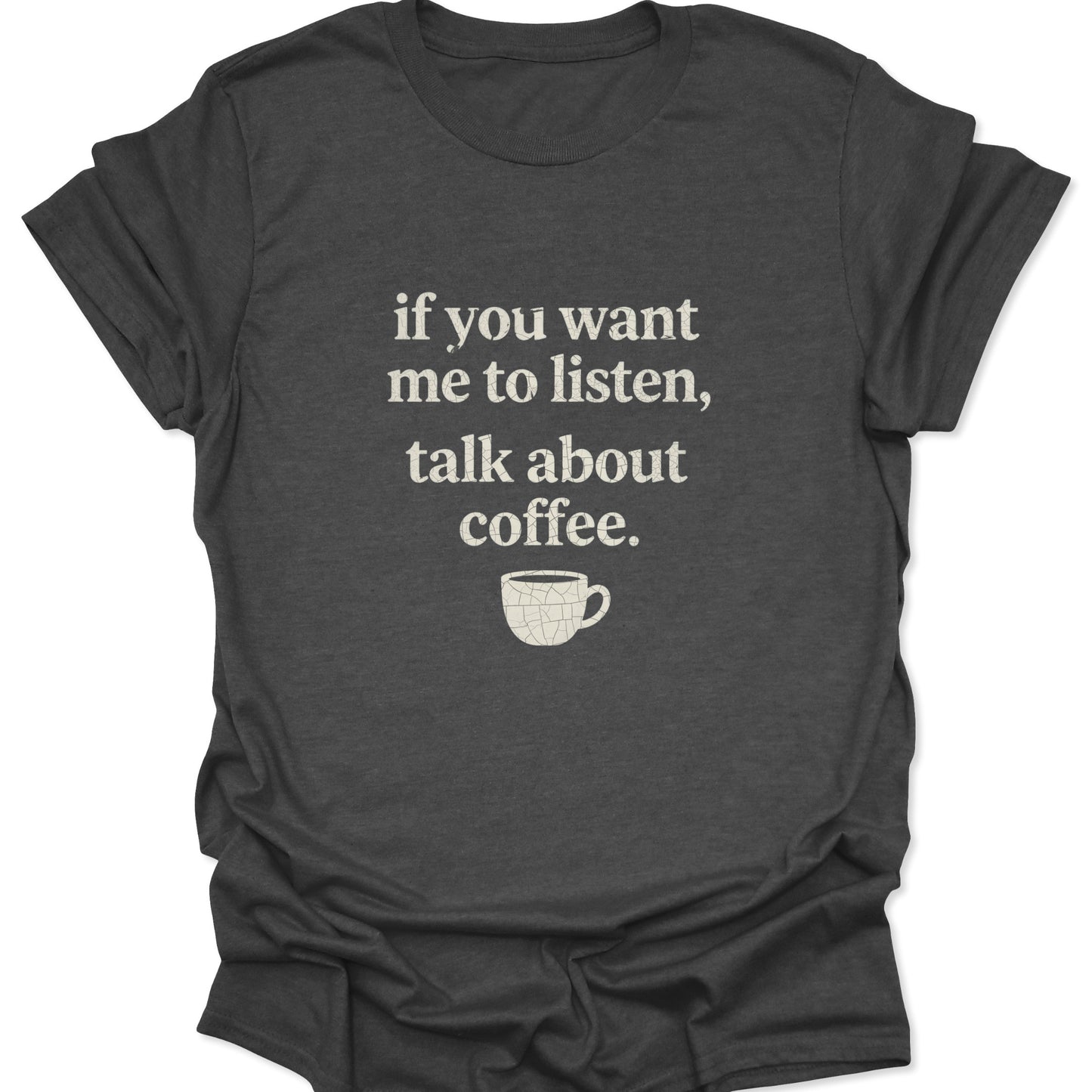 A dark heather gray shirt displaying a minimalist "talk about coffee" quote in a vintage-style distressed white font with a small textured coffee mug graphic below.