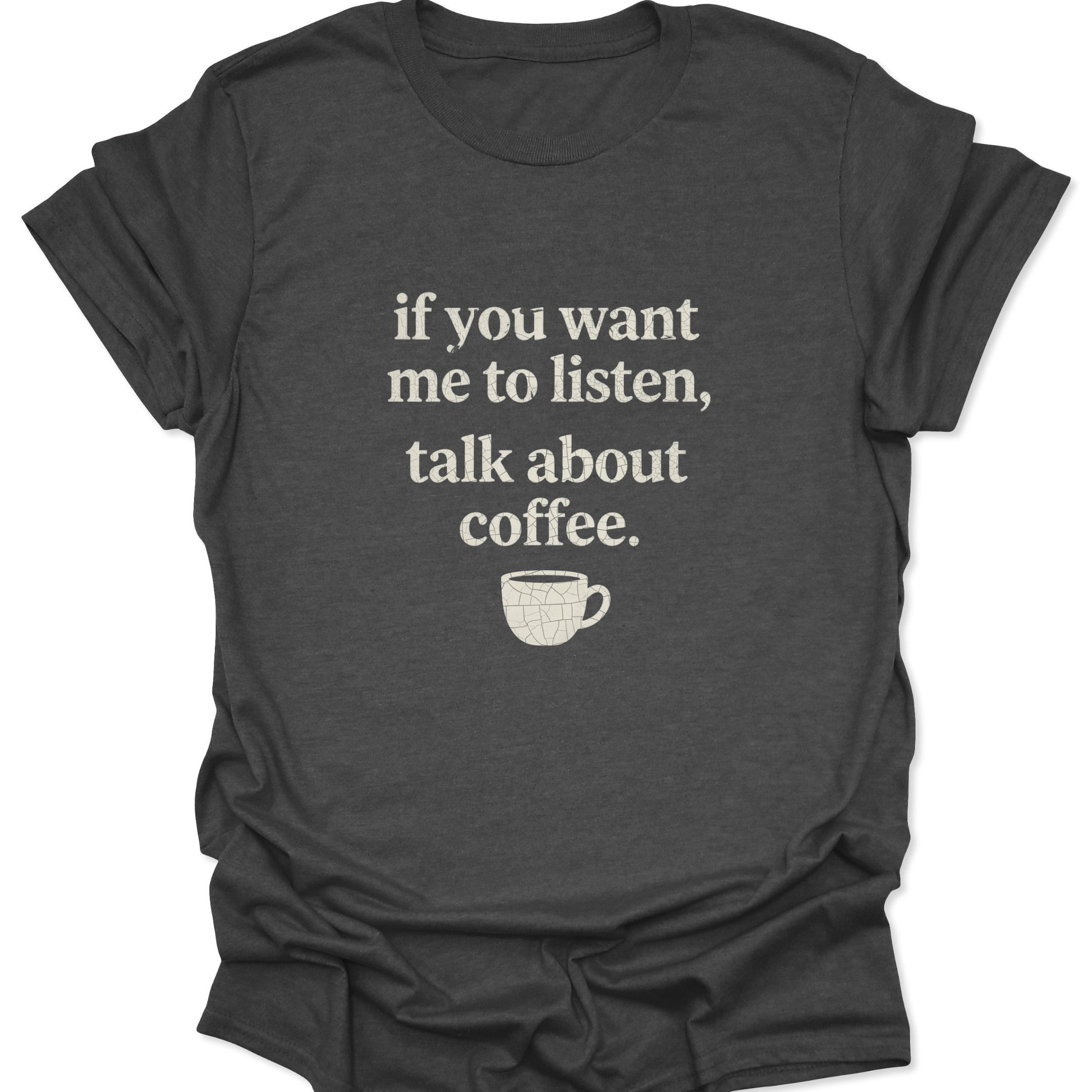 A dark heather gray shirt displaying a minimalist "talk about coffee" quote in a vintage-style distressed white font with a small textured coffee mug graphic below.